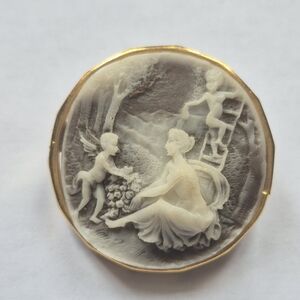 Vintage cameo-style brooch featuring a woman and two cherubs